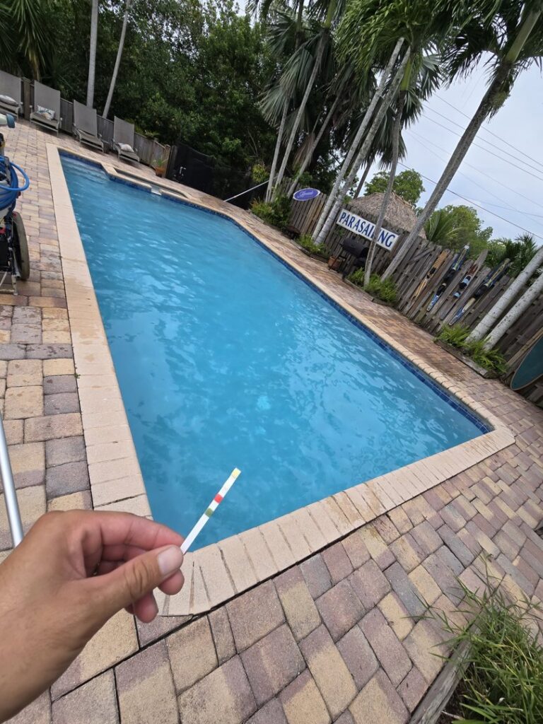 A professional from Summer Breeze Pool Services testing pool water with a test strip in Fayetteville, GA.