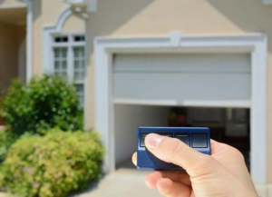 A hand using a garage door opener remote, demonstrating functionality provided by Delta Garage Doors in Cleveland, OH