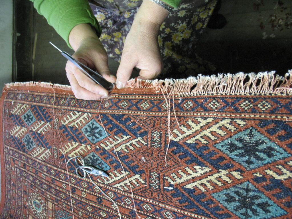 Skilled hands meticulously repairing the delicate fringe of an oriental rug at Zakian Rug Cleaning in Philadelphia, PA