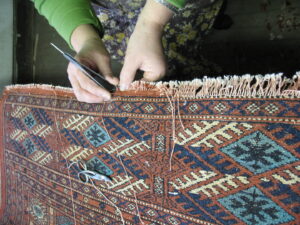 Skilled hands meticulously repairing the delicate fringe of an oriental rug at Zakian Rug Cleaning in Philadelphia, PA