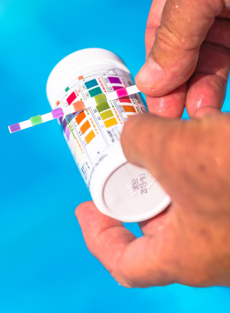 Hands holding a test strip to check pool water chemical levels for Water Works Pool & Spa Service in Madison, WI