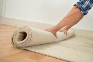 Hands unrolling a new roll of carpet during an installation by JCB Interiors in Stamford, CT