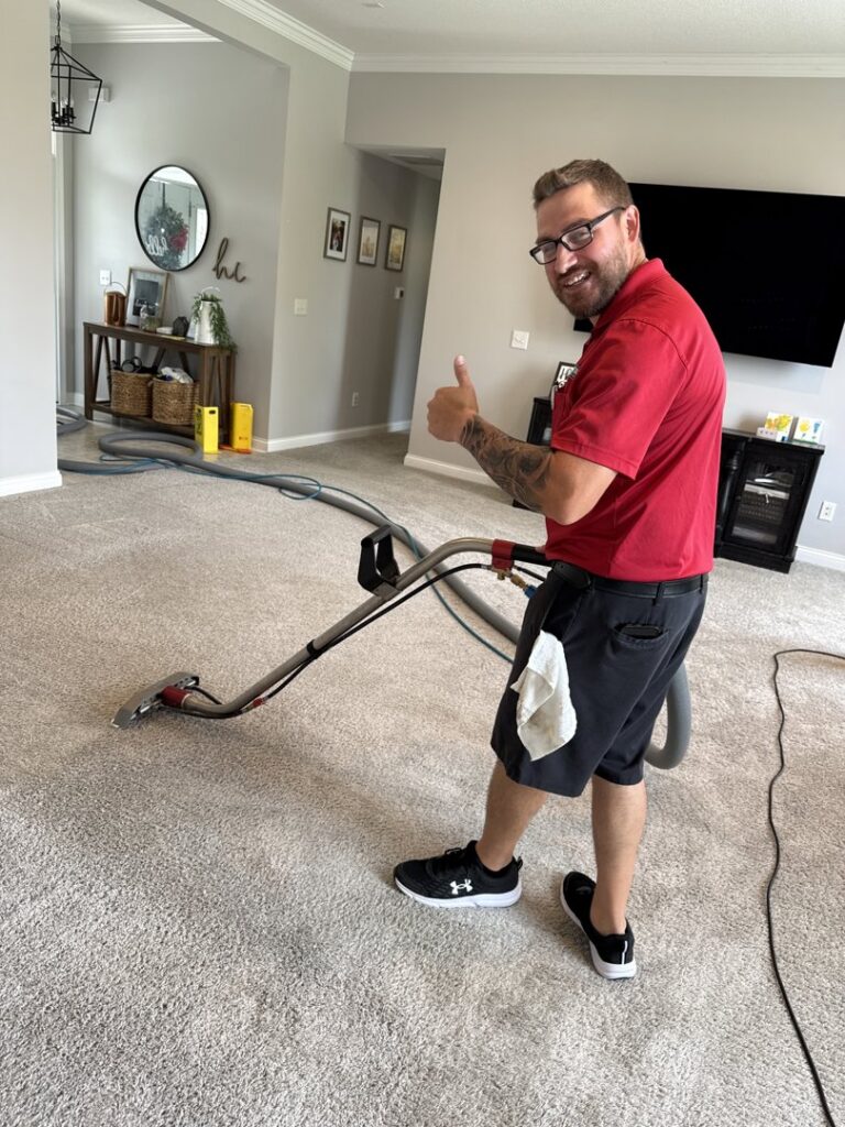 A smiling technician giving a thumbs up while performing carpet cleaning services at Referral Cleaning and Restoration Inc. in Fort Wayne, IN.