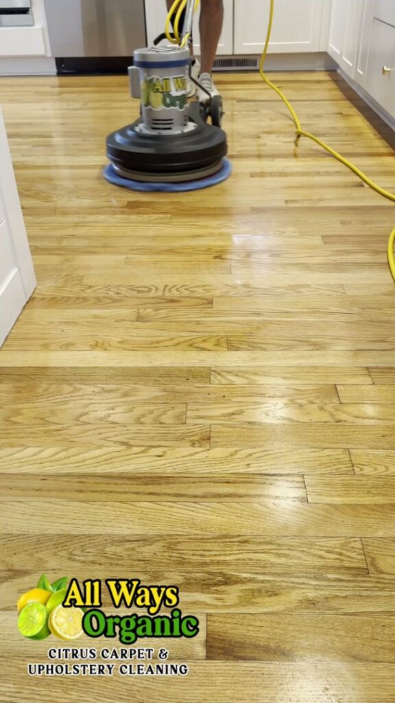 A professional cleaning technician operating a floor cleaning machine on a hardwood floor by All Ways Organic Citrus Carpet & Upholstery Cleaning in Wilmington, NC.