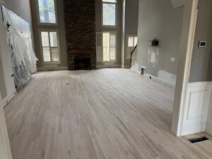 Newly installed light hardwood flooring in a spacious living room, indicating a professional flooring job by Peach Design Inc. in Atlanta, GA.