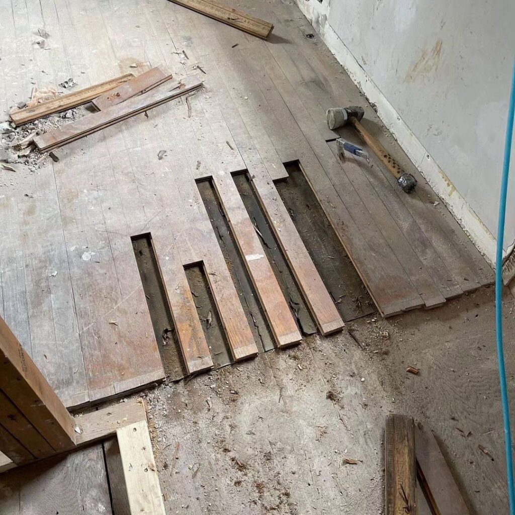 Hardwood floor repair in progress, with damaged planks removed and new ones being fitted by Isad Home Floor in Bridgeport, CT.