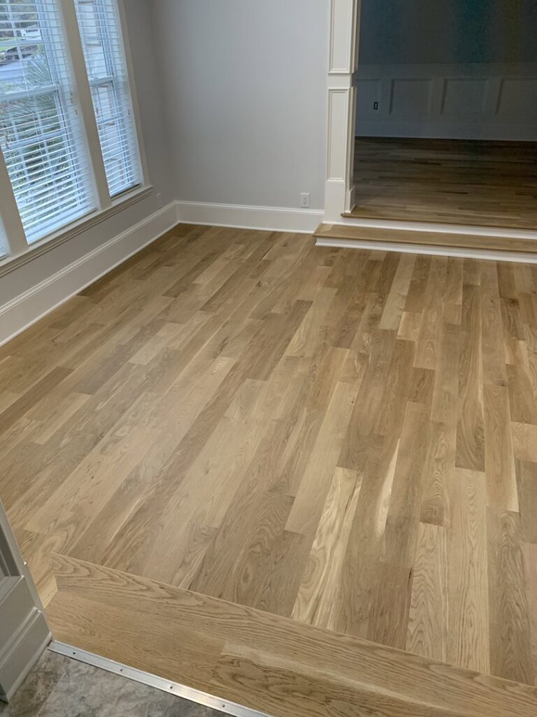 Detailed view of a hardwood floor installation with a clean transition by Peach Design Inc. in Atlanta, GA.