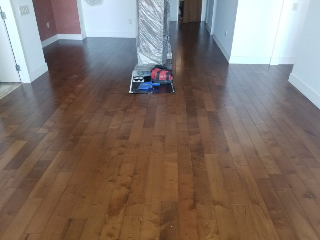 A room showcasing a dark brown hardwood flooring installation, with tools visible, completed by LACarpetWarehouse in Los Angeles, CA.