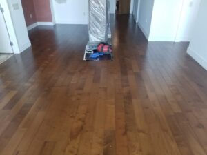 A room showcasing a dark brown hardwood flooring installation, with tools visible, completed by LACarpetWarehouse in Los Angeles, CA.