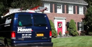 A Hawn Heating and Air Conditioning service van with ladders, parked at a residential home in Rochester, NY.