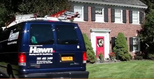 A Hawn Heating and Air Conditioning service van with ladders, parked at a residential home in Rochester, NY.