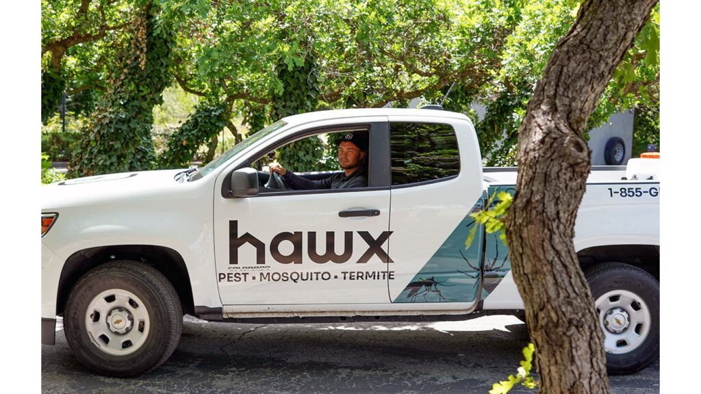 A Hawx Pest Control truck with a technician inside, ready for service in San Antonio, TX.