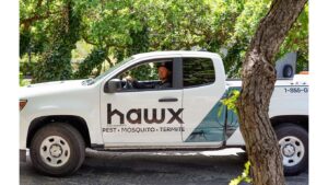 A Hawx Pest Control truck with a technician inside, ready for service in San Antonio, TX.