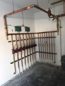 A heating distribution manifold system with copper piping and valves installed by Boiler Man Plumbing & Heating in Palmer, AK