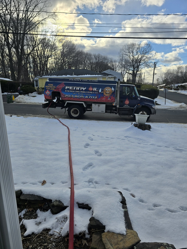 A Penny Oil Energy Distributors LLC truck delivering heating oil to a home in Waterbury, CT, during winter.