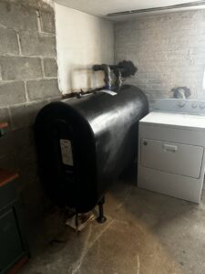 A large black heating oil tank installed in a basement by L&SON Heat AC Tech in Yonkers, NY.