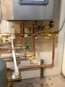 Two red circulation pumps and copper piping for a heating system installed by Green Planet Solutions Corporation in Moscow, PA.