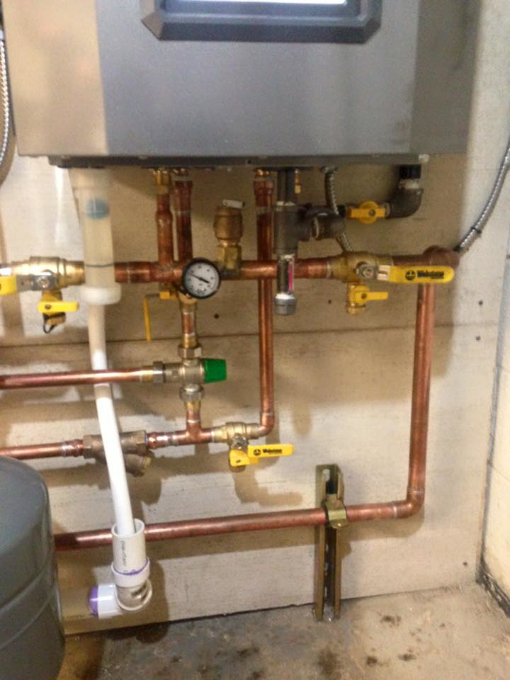 Two red circulation pumps and copper piping for a heating system installed by Green Planet Solutions Corporation in Moscow, PA.