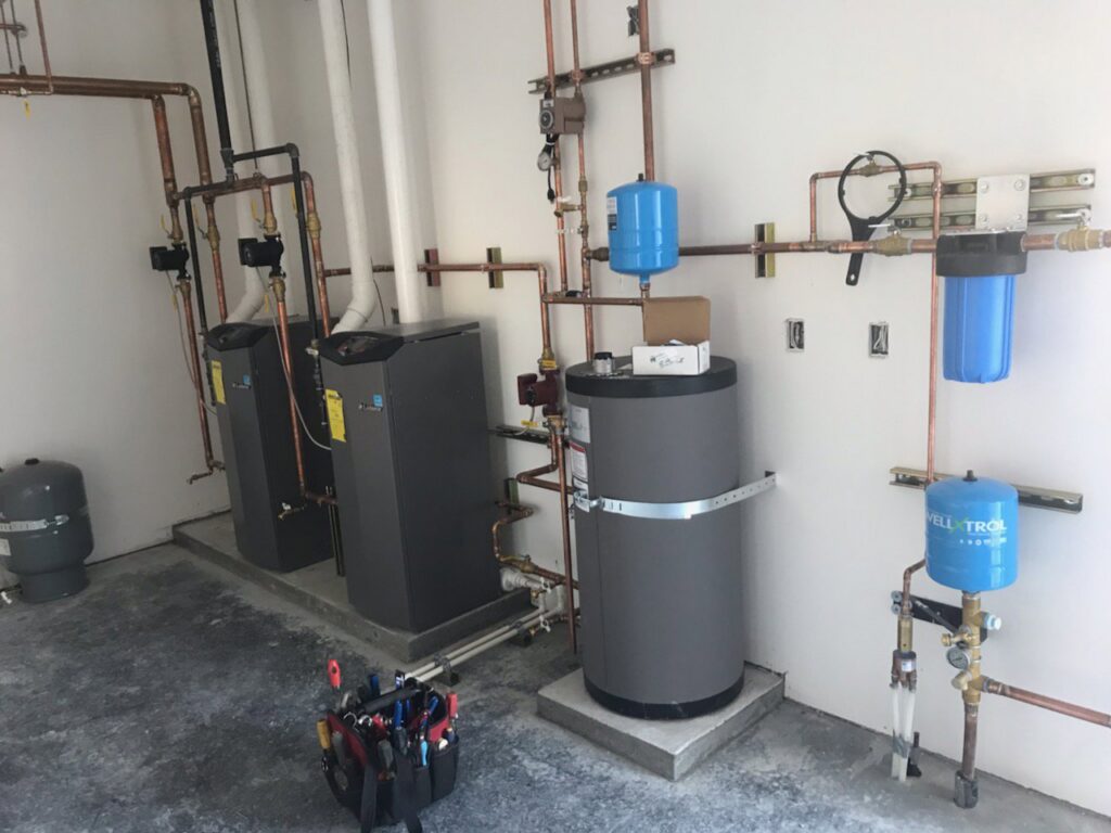 A newly installed heating system with multiple boilers, copper piping, and water filters by Boiler Man Plumbing & Heating in Palmer, AK