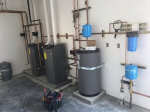 A newly installed heating system with multiple boilers, copper piping, and water filters by Boiler Man Plumbing & Heating in Palmer, AK