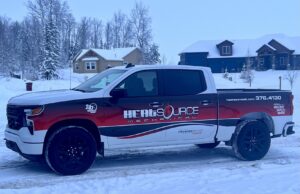 A HeatSource Mechanical service truck parked in a snowy residential area in Wasilla, AK.
