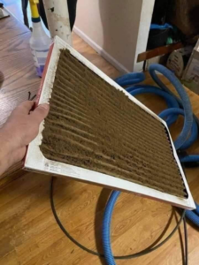 A hand holding a heavily clogged and dirty air filter, showing the need for HVAC cleaning by JJ Duct Cleaning in Aurora, IL