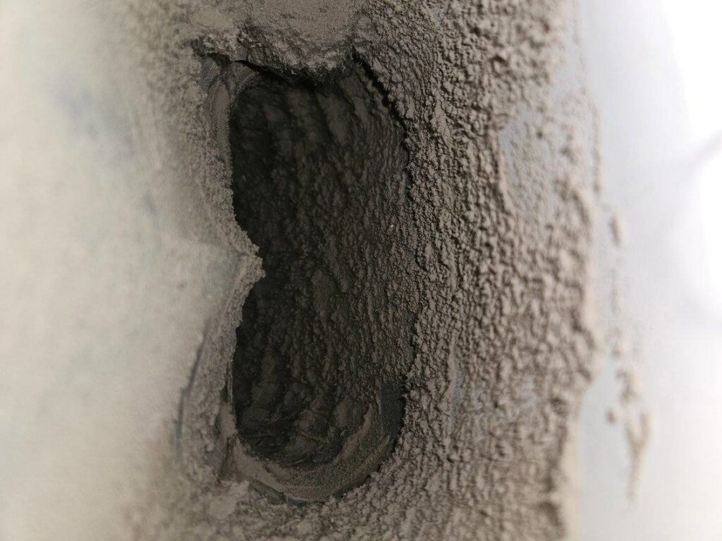 A heavily clogged dryer vent opening caked with lint and dust, showing the need for professional cleaning from Pro Power Air Duct & Dryer Vent Cleaning in Kenosha, WI.