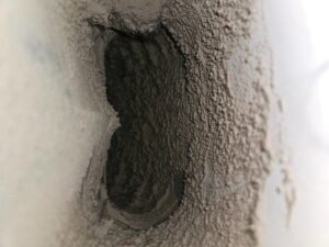 A heavily clogged dryer vent opening caked with lint and dust, showing the need for professional cleaning from Pro Power Air Duct & Dryer Vent Cleaning in Kenosha, WI.