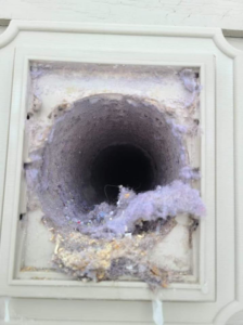 A heavily clogged exterior dryer vent opening filled with lint, demonstrating the need for service from Aero Brush Duct Cleaning in Billings, MT.