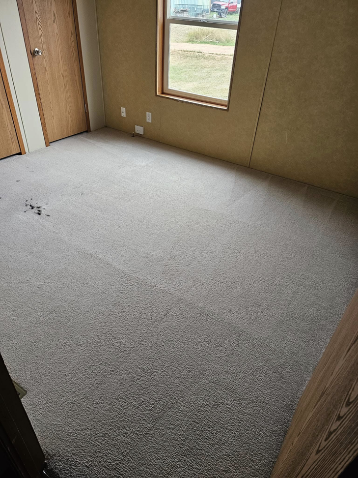 A heavily stained carpet in a room before deep cleaning by Peterson's Carpet & Air Duct Cleaning in Dickinson, ND.