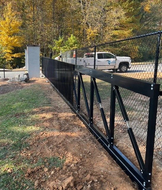 Installation of a heavy-duty black sliding gate with chain-link fencing by First Fence of Georgia in Kennesaw, GA.