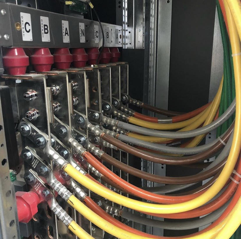 Close-up of heavy-gauge electrical cables connected to busbars inside a panel by Harbour Electric in Wilmington, NC.