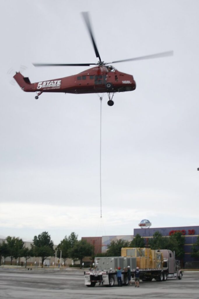 A helicopter lifting heavy HVAC equipment for a commercial installation by Chapman Air and Heat in Dallas, TX