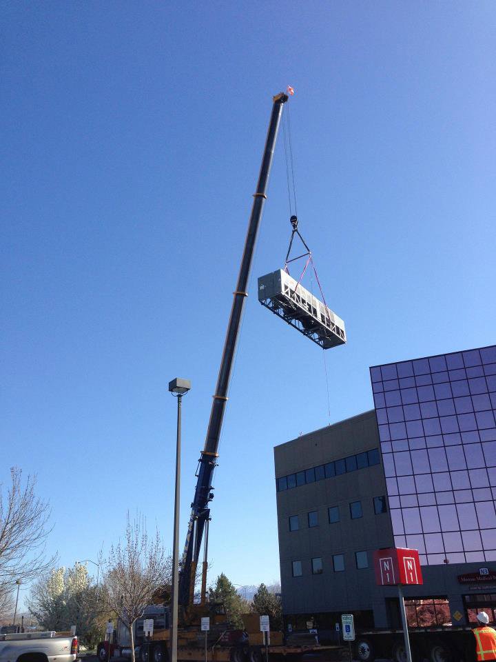 A helicopter lifting a large commercial HVAC unit for rooftop installation by American Mechanical Corp in Caldwell, ID