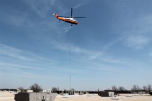 A helicopter lifting a large rooftop HVAC unit for installation or replacement by DMC Service, Inc. in Olathe, KS.