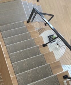 A modern herringbone pattern carpet runner installed on a wooden staircase by Floors Next Day in Austin, TX.