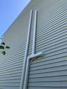 PVC exhaust and intake pipes for a high-efficiency furnace or boiler on the exterior of a home, installed by Hyper Fusion Heating & Cooling in Waterbury, CT.