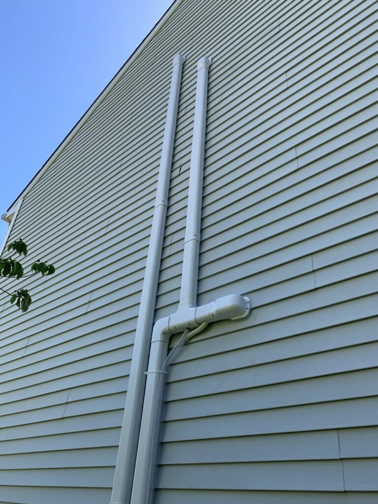PVC exhaust and intake pipes for a high-efficiency furnace or boiler on the exterior of a home, installed by Hyper Fusion Heating & Cooling in Waterbury, CT.
