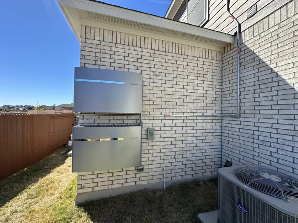 An Enphase home battery storage system installed on the exterior brick wall by Rubio Electrical Innovations LLC in San Antonio, TX.