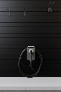 A sleek home electric vehicle charger installed on a black slatted wall by Dr. Sparky in Nashville, TN