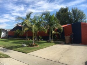 A home undergoing fumigation service with orange and blue tenting by Intensive Pest Control in Long Beach, CA.