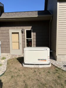 A Generac generator installed on a concrete pad next to a home by Great Lakes Power Generation in Williamsburg, MI.