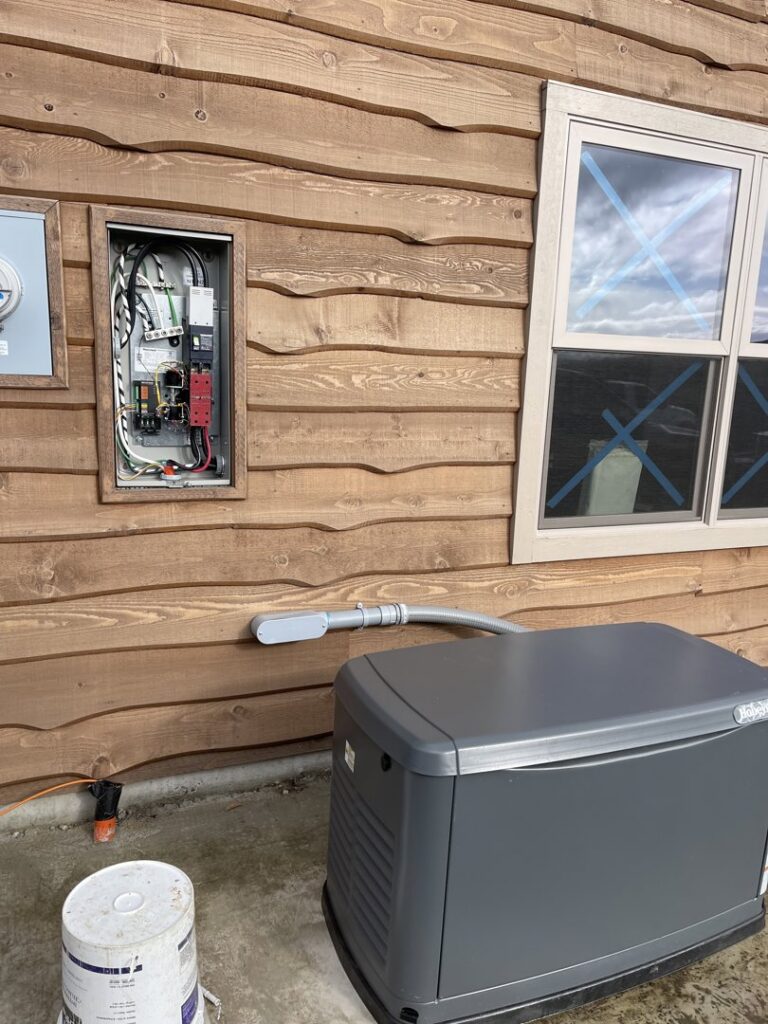An outdoor home generator with its electrical connection to the house, installed by Freedom Electric Construction, LLC in Eugene, OR.