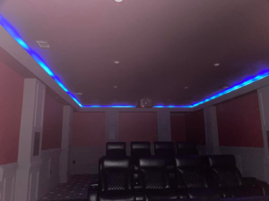 A home theater room with custom LED strip lighting and recessed lights installed by Heritage Electric in Bluffton, SC.