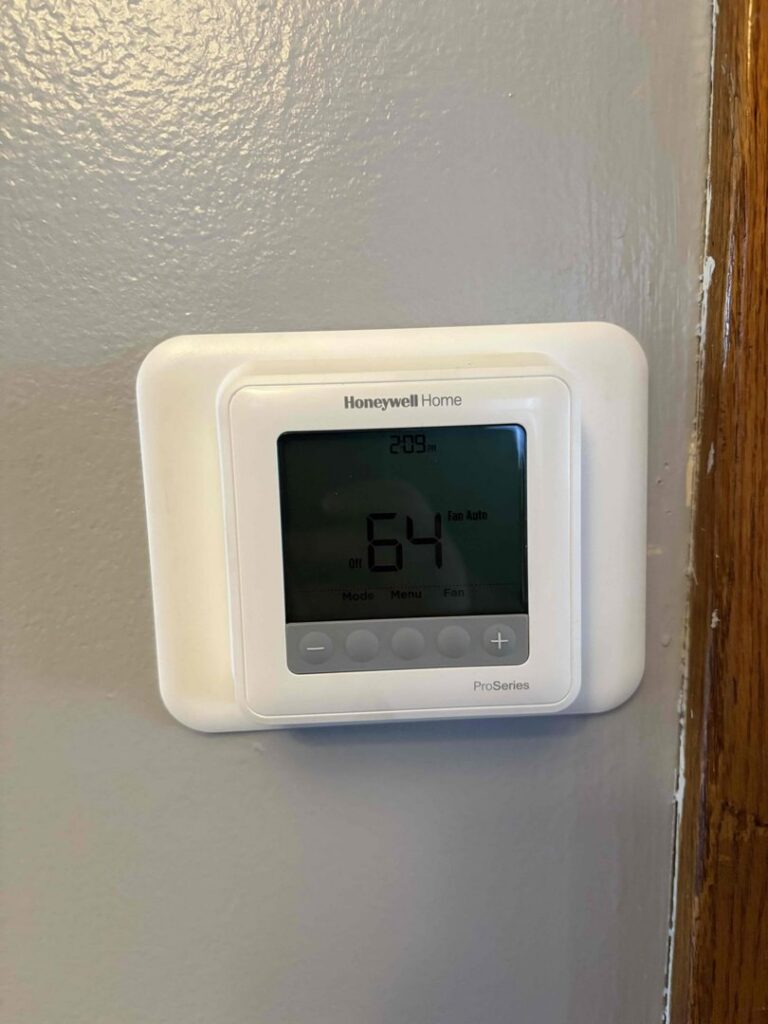 A Honeywell Home ProSeries thermostat displaying 64 degrees, installed by Service Pro Titans in Chicago, IL.