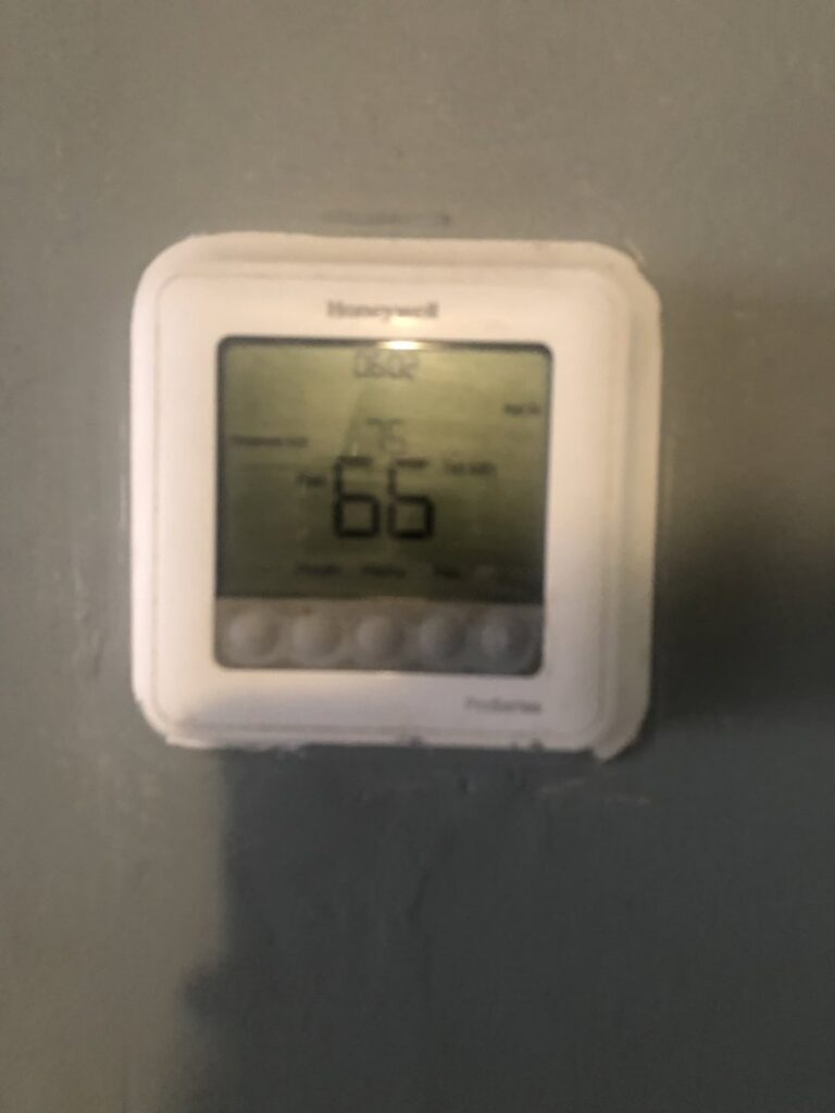 A Honeywell thermostat displaying 66 degrees with heat on, serviced by Elements Heating & Cooling LLC in Minneapolis, MN.
