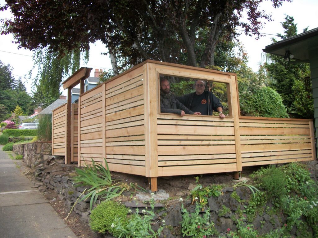 Two fencing contractors standing behind a newly built horizontal slat fence by Fix-A-Fence LLC in Portland, OR.