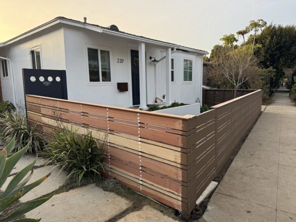 A horizontal slat fence under construction, showing different stages of panel installation by Harwell Fencing & Gates Inc. in Los Angeles, CA.