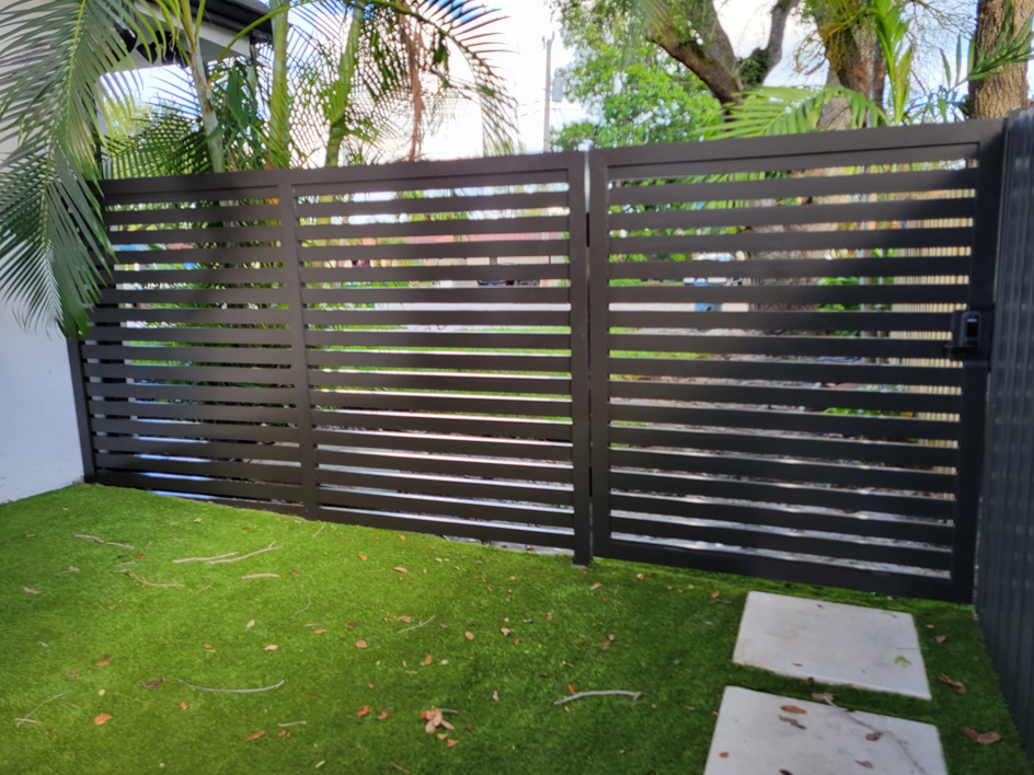 A modern dark gray horizontal slat privacy gate and fence installed by Southeastern Fence Corp. in Pembroke Pines, FL.