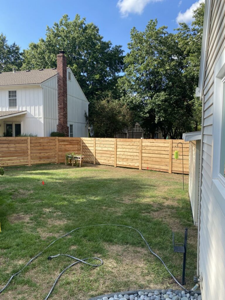 A modern horizontal slat wood fence installed in a residential backyard by Sergio's Fence in Kansas City, KS.